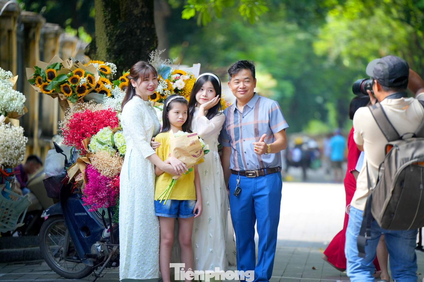 Một gia đình tranh thủ chụp ảnh với gánh hoa sau khi đã ghé thăm Lăng Bác, Cột cờ Hà Nội, Hoàng thành Thăng Long.