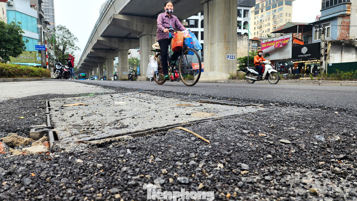 Tại nhiều điểm ven lề phần trải thảm mới, các mảnh đá dăm, đá vụn cũng nằm rải rác. Ngấm thêm nước từ những cơn mưa dài ngày tạo thành những ổ "trượt lốp, mất lái" cho người tham gia giao thông. Trong ảnh: Một nắp hố ngầm lộ thiên thấp hơn mặt đường mới khoảng 5cm, bao quanh là các mảnh đá dăm đổ vội.