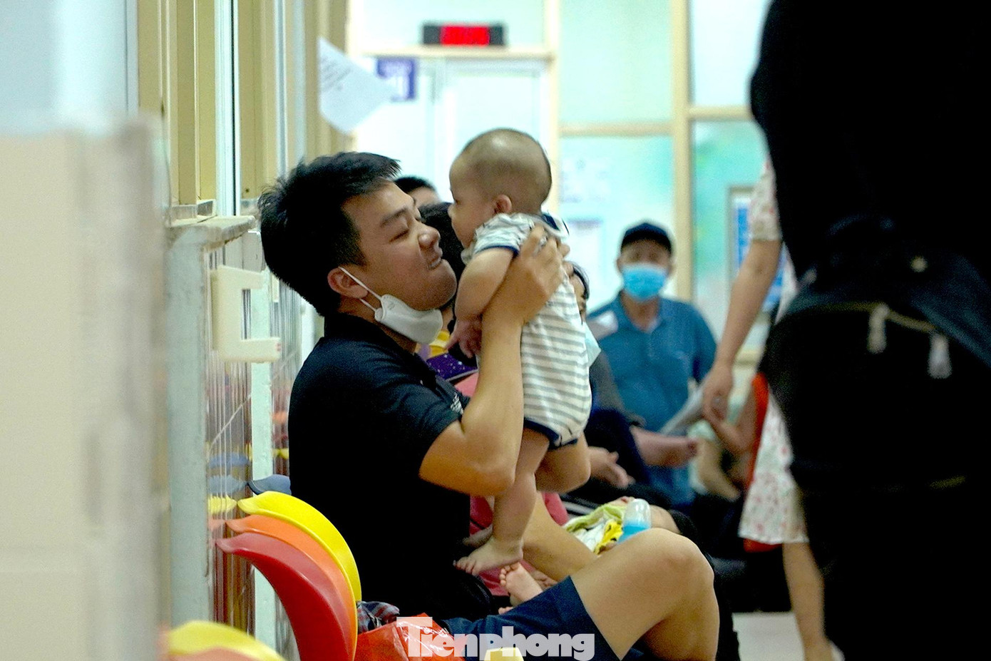 Một người bố tranh thủ nựng con trong thời gian chờ đến lượt thăm khám.