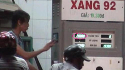 Trong khi một nhân viên đổ xăng thì một nhân viên khác nhanh tay bấm số gian lận từ 17.577 đồng (ảnh trên) thành 20.000 đồng (ảnh dưới) (ảnh chụp từ clip quay tại cửa hàng xăng dầu 133 Hùng Vương, P.6, Q.6 tối 10-3-2011) - Ảnh: Sơn Lâm