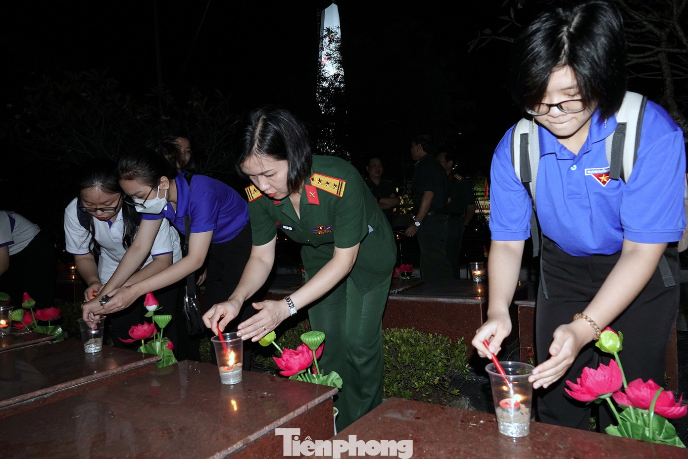 Thượng tá Phan Ái Xuân - Phó trưởng Ban Phụ nữ Quân đội cùng ĐVTN Quân đội và Thành phố Cần Thơ thắp nến tri ân tại phần mộ các Anh hùng liệt sĩ ở Nghĩa trang Liệt sĩ Thành phố Cần Thơ, tối 26/7. Ảnh: Nguyễn Minh