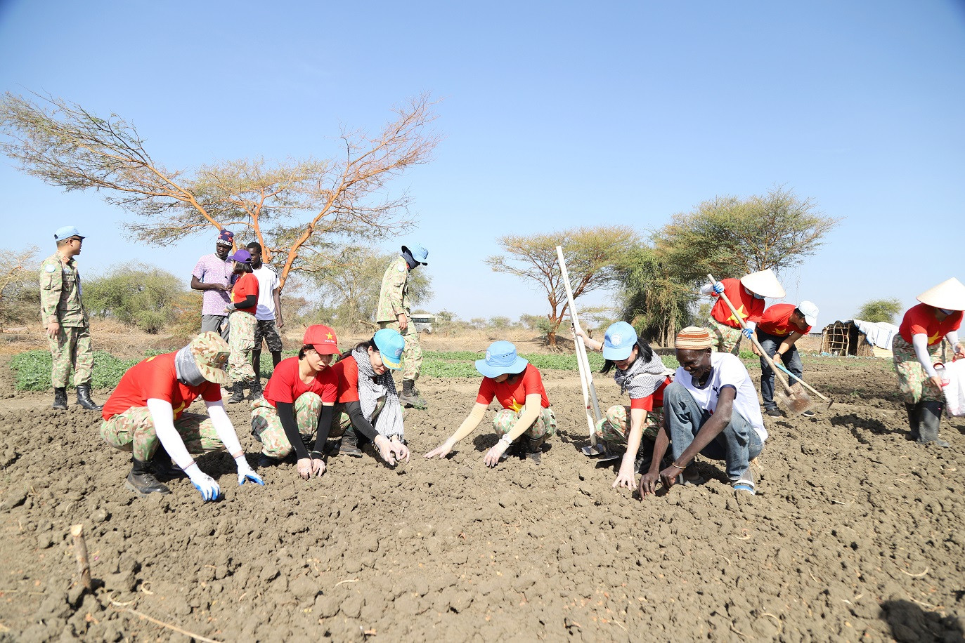 Nữ quân nhân thuộc Đội Công binh Việt Nam giúp đỡ người dân địa phương trồng rau xanh cải thiện cuộc sống