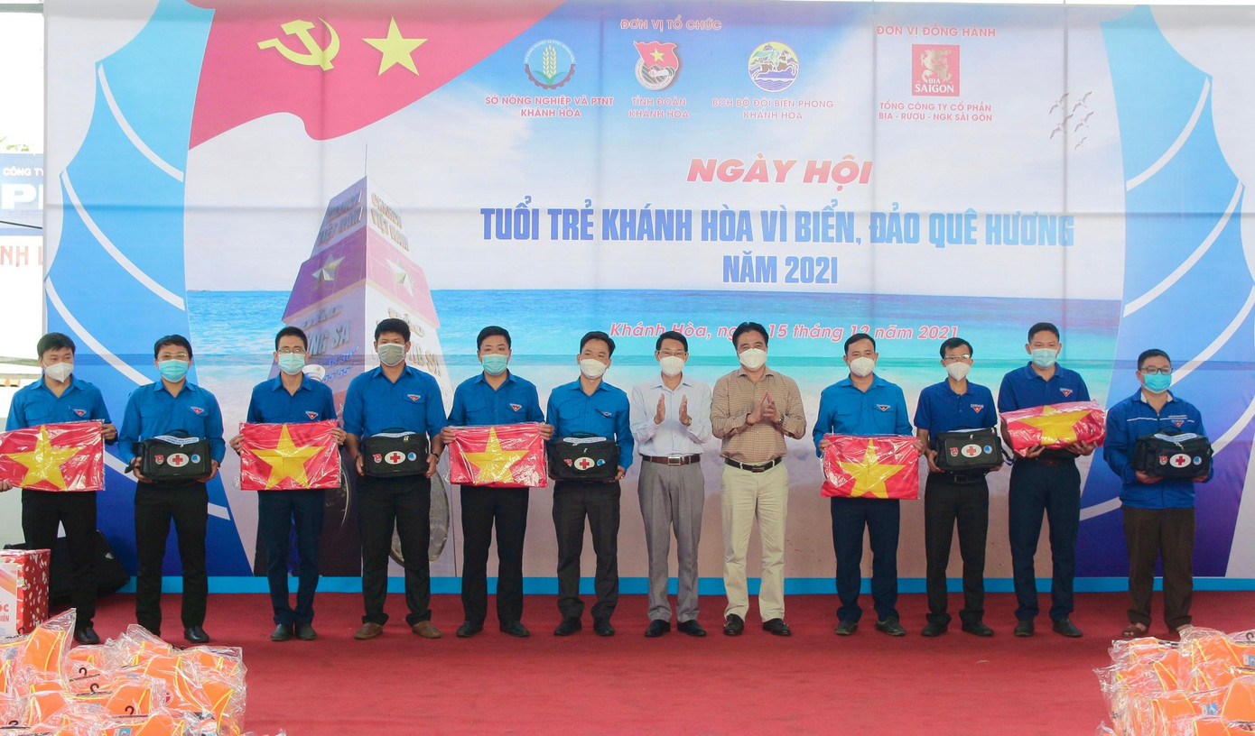 Ông Nguyễn Khắc Toàn và ông Đinh Văn Thiệu trao thiết bị giám sát hành trình (ảnh trên), cờ Tổ quốc và túi y tế cho ngư dân trẻ bám biển.