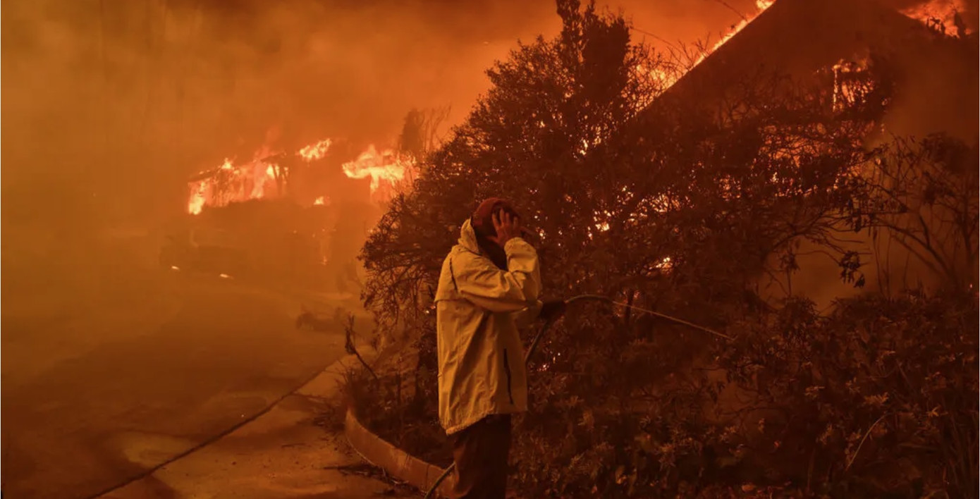 Một người dân ở Palisades dùng vòi tưới vườn để dập đám cháy. (Ảnh: NYT)