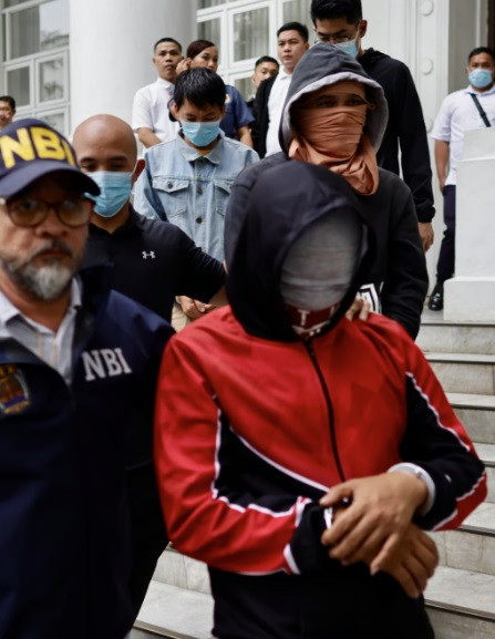 Nghi phạm họ Deng (áo xanh đậm, che mặt) bị lực lượng chức năng Philippines dẫn giải. (Ảnh: EPA-EFE) Nghi phạm họ Deng (áo xanh đậm, che mặt) bị lực lượng chức năng Philippines dẫn giải. (Ảnh: EPA-EFE)