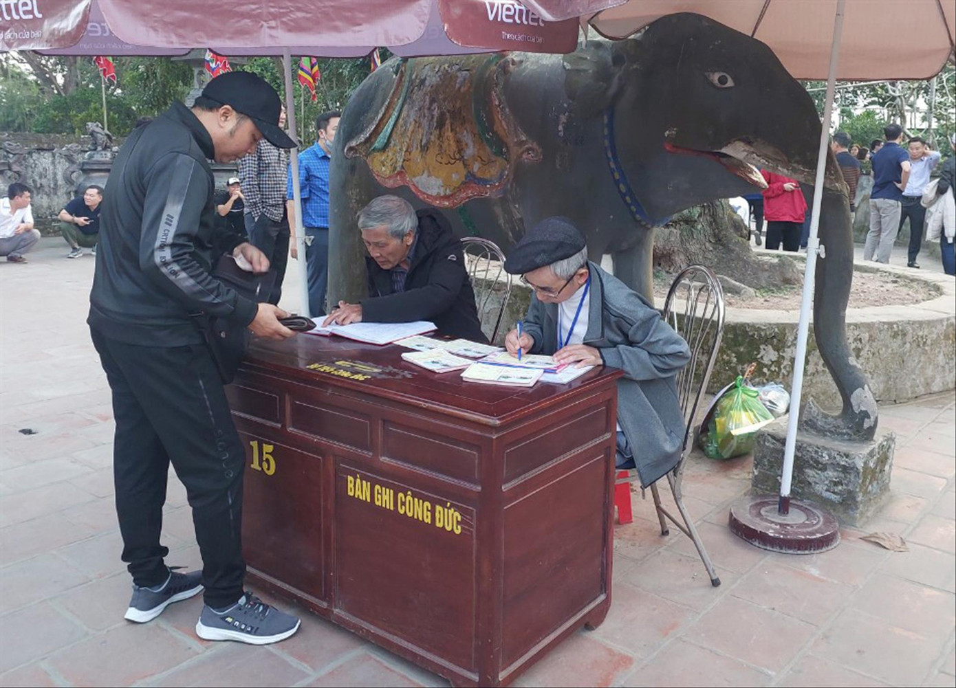 Người dân ghi phiếu tiền công đức tại Đền Trần (Nam Định). Ảnh: QN Người dân ghi phiếu tiền công đức tại Đền Trần (Nam Định). Ảnh: QN