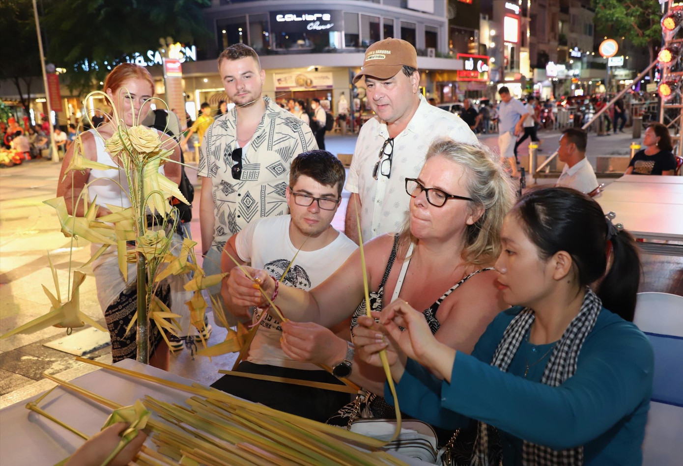 Du khách tập xếp lá dừa trên phố đi bộ Nguyễn Huệ. Ảnh: Ngô Tùng
