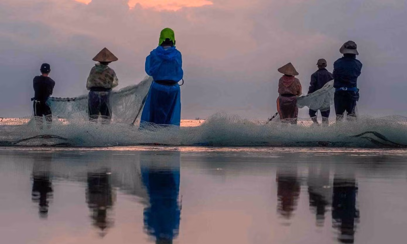 Ngư dân kéo lưới cá dưới ánh bình minh tại bờ biển Cửa Đại