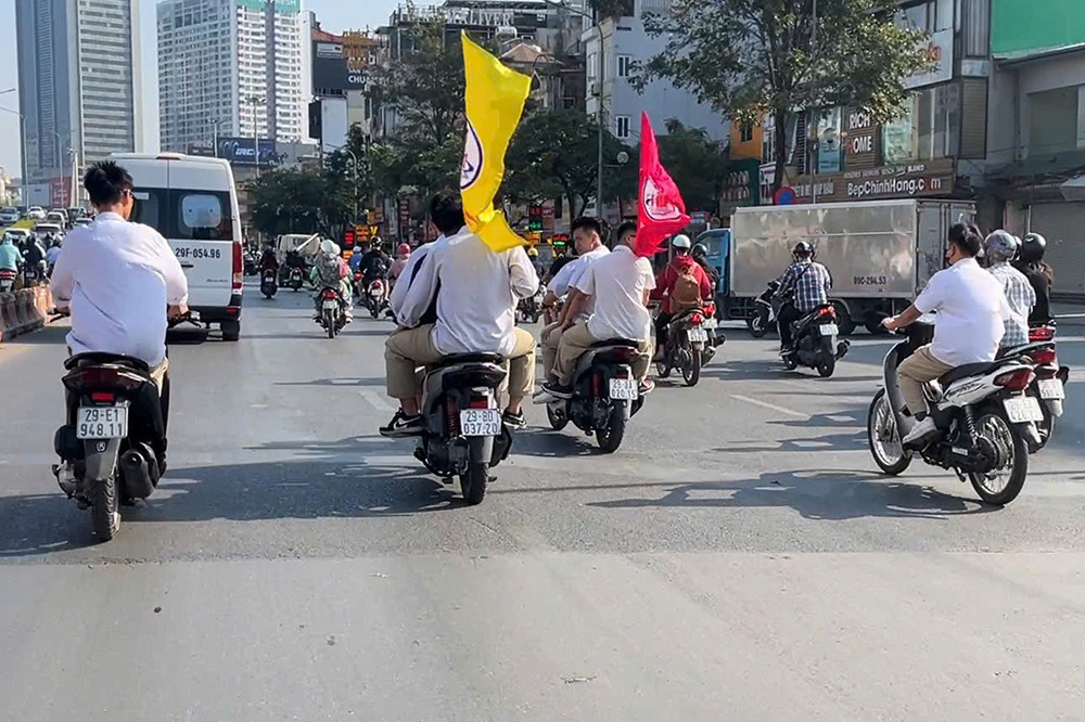 Nhóm học sinh điều khiển mô tô "kẹp ba", không đội mũ bảo hiểm. Một số trường hợp còn khua khoắng cờ trên đường. Ảnh chụp màn hình