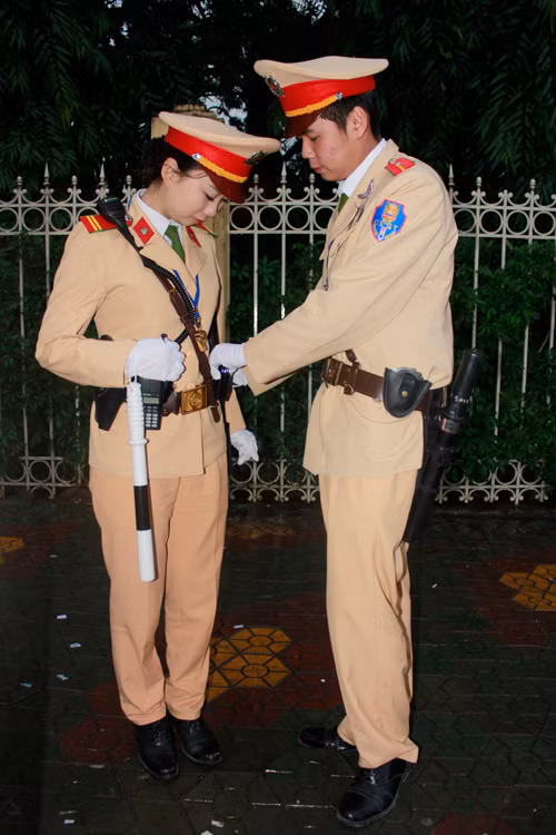 Đồng nghiệp nam chỉnh quân phục cho nữ cảnh sát giao thông đội 7 trước giờ làm nhiệm vụ. Ảnh: Tuấn Nguyễn.
