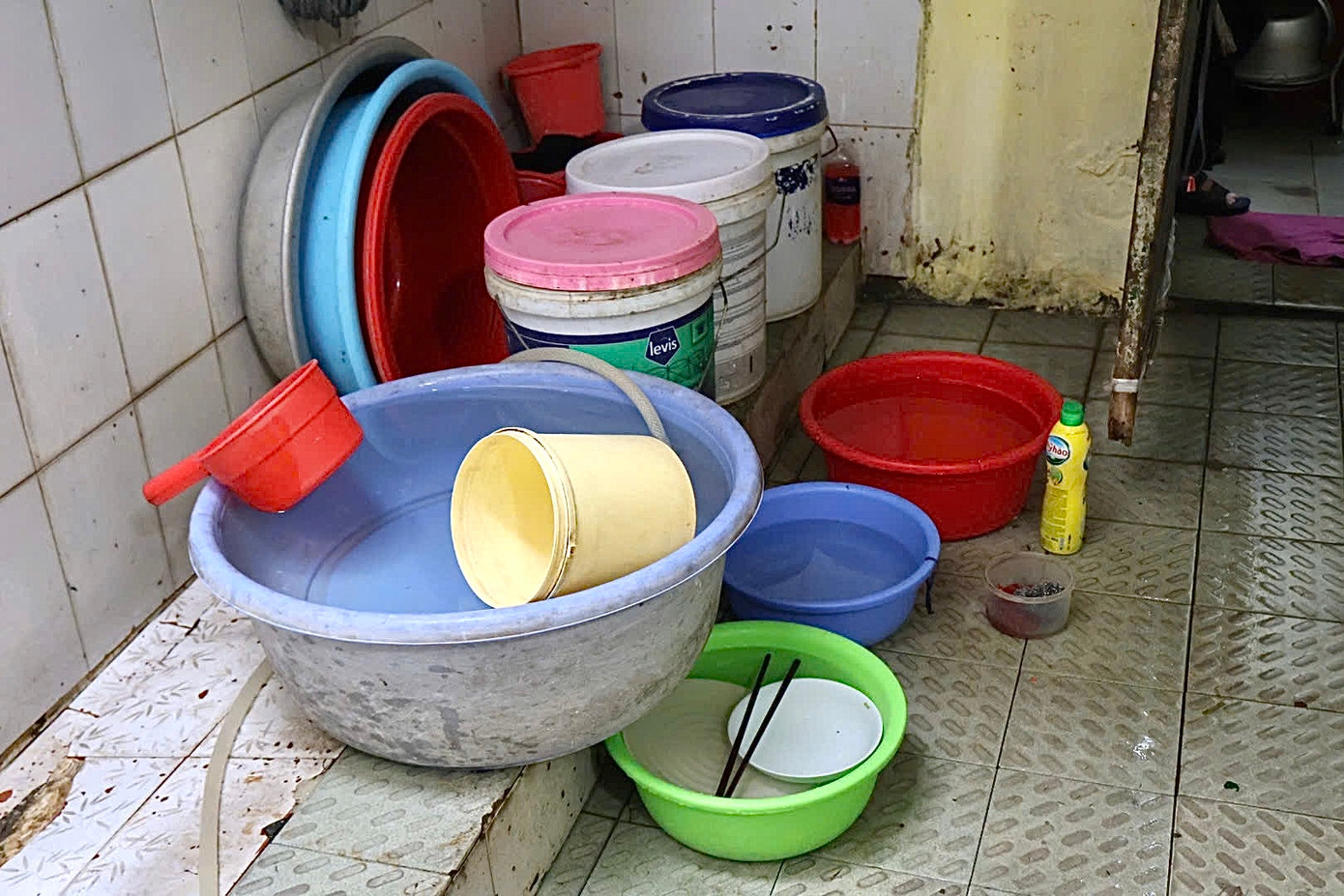 “Tôi đã làm ở đây 25 năm, ngày nào cũng làm từ 5h30 đến 22h. Vì nơi này xây dựng đã lâu và chưa được cải tạo nên nơi đây đã xuống cấp nghiêm trọng; cửa bị mối mọt có cánh đóng được có cánh chỉ khép hờ được...", bà Xuân cho biết. Trong ảnh là xô đựng nước để dội sau mỗi lần đi vệ sinh. Ảnh: Hồng Ngọc.
