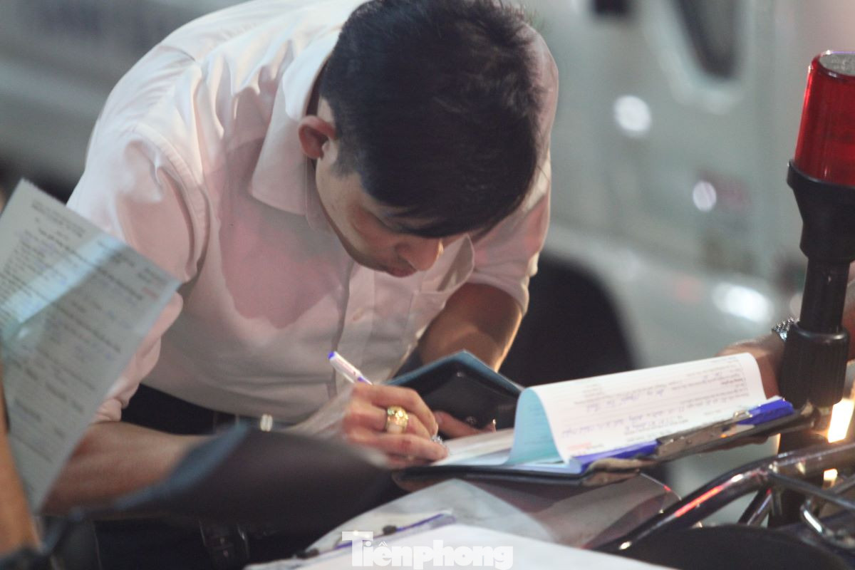 Tài xế ký biên bản vi phạm hành chính với lỗi đậu xe trên vỉa hè.