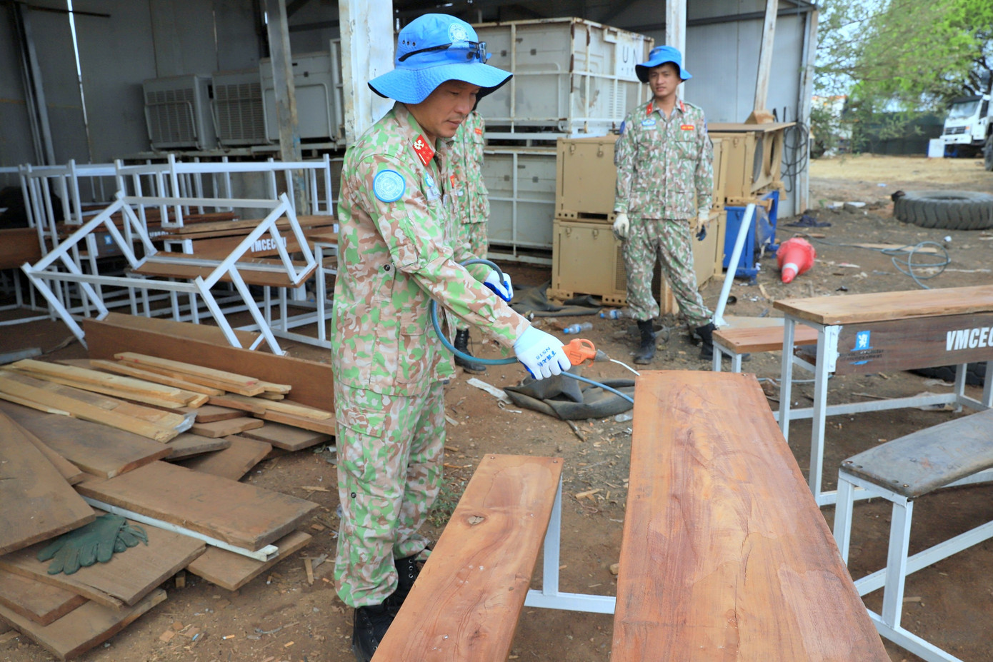 Nhân viên Phân đội Công trình 2 (Đội Công binh số 3) gia công bàn liền ghế từ vật liệu tận dụng.