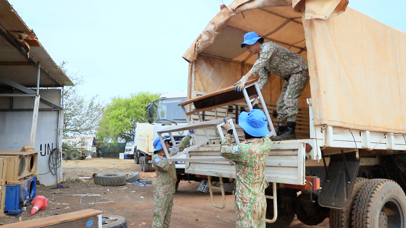 Nhân viên Phân đội Công trình 2 (Đội Công binh số 3) bốc xếp, vận chuyển thành phẩm bàn liền ghế đi trao tặng học sinh ở Abyei.
