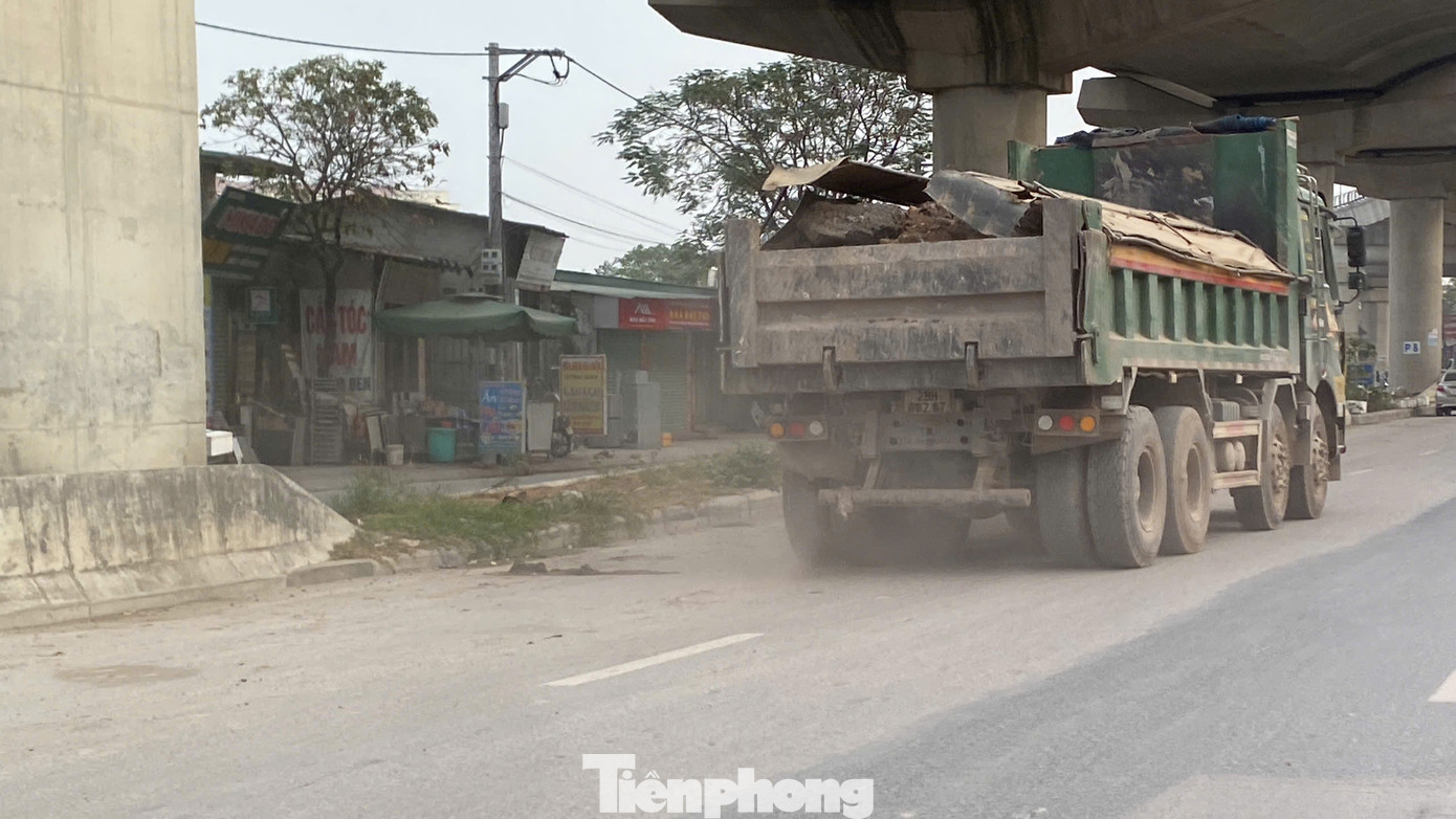 Các xe tải chở đất đá từ dự án ra vào, bánh xe cuốn bụi từ mặt đường bay lên mù mịt.