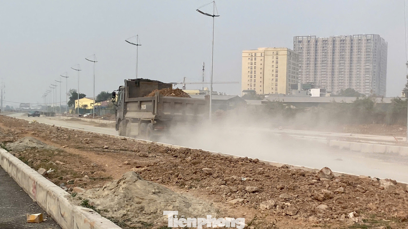 Xe tải chở đất không che chắn, lốp xe cuốn cát, bụi bay mịt mù. Chỉ sau 5 phút có mặt tại đây, xe máy và quần áo của chúng tôi bị phủ một lớp bụi trắng xoá.