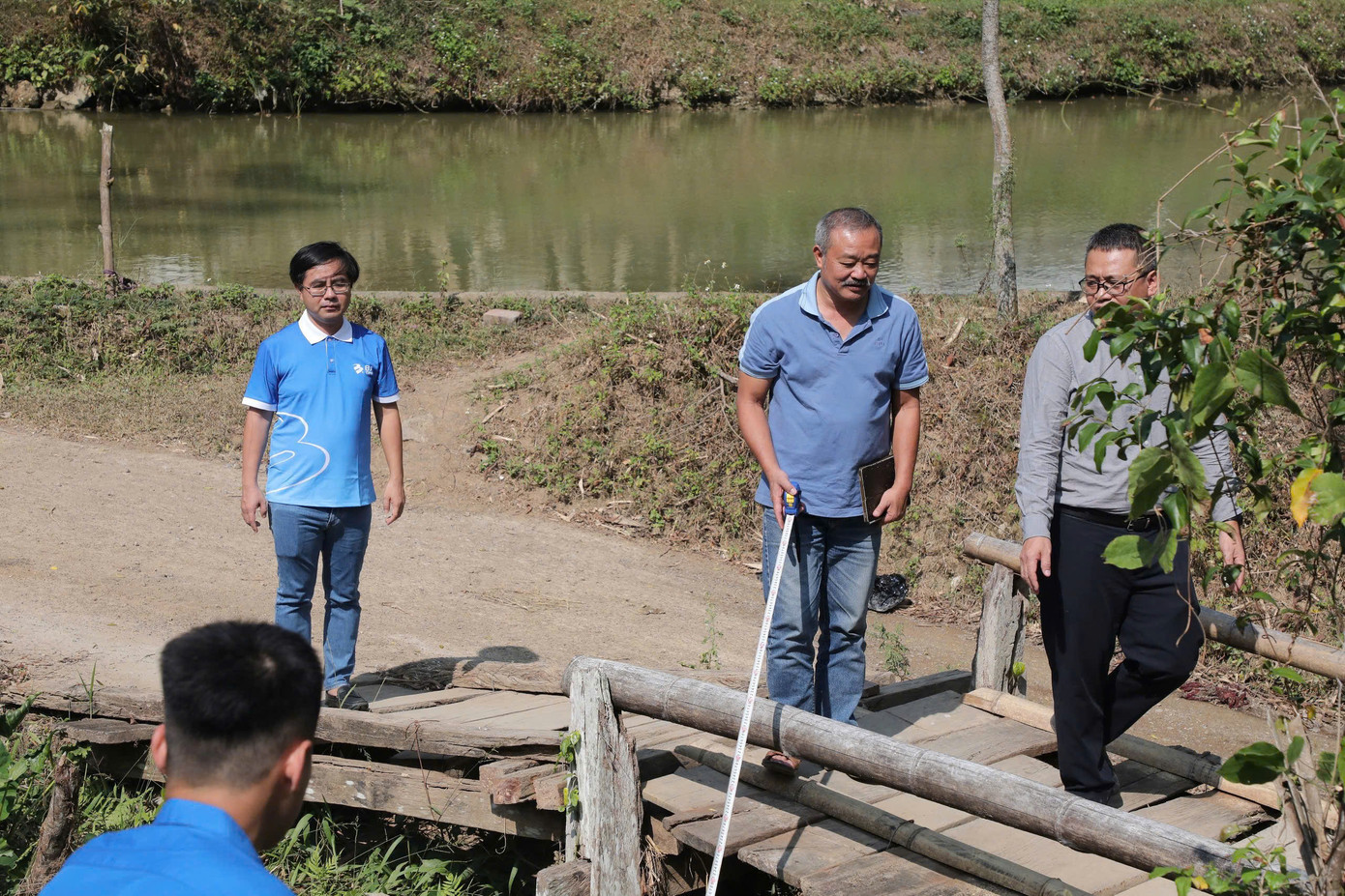 Trước đó, với mong muốn có đóng góp thiết thực hỗ trợ người dân vực dậy sau bão Yagi, anh Đào Thanh Anh, Chủ tịch BA GPS đề nghị báo Tiền Phong tìm kiếm và kết nối xây dựng một công trình dân sinh. Sau khi thống nhất việc xây dựng cây cầu này, cá nhân anh Đào Thanh Anh và cán bộ công nhân viên của BA GPS đã quyên góp tiền để xây dựng. Trong ảnh, anh Đào Thanh Anh (đứng ngoài cùng bên trái) khi đi khảo sát địa điểm xây dựng cầu tại thôn Nà Dài vào tháng 11/2024.