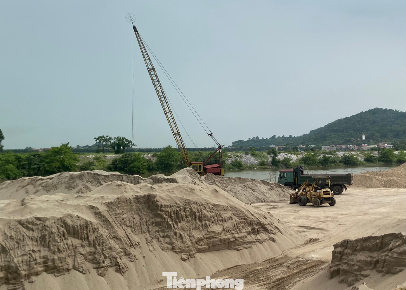 Các núi cát khổng lồ được chất cao cả chục mét nằm ngay sát bờ sông.