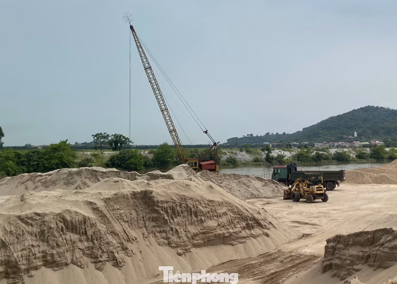 Các núi cát khổng lồ được chất cao cả chục mét nằm ngay sát bờ sông.