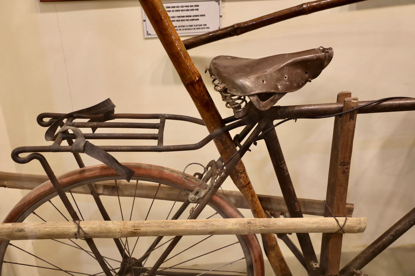 Buộc vào trục yên xe một đoạn tre, cao hơn yên khoảng 50cm để cầm, vừa giữ thăng bằng xe, vừa đẩy xe đi.