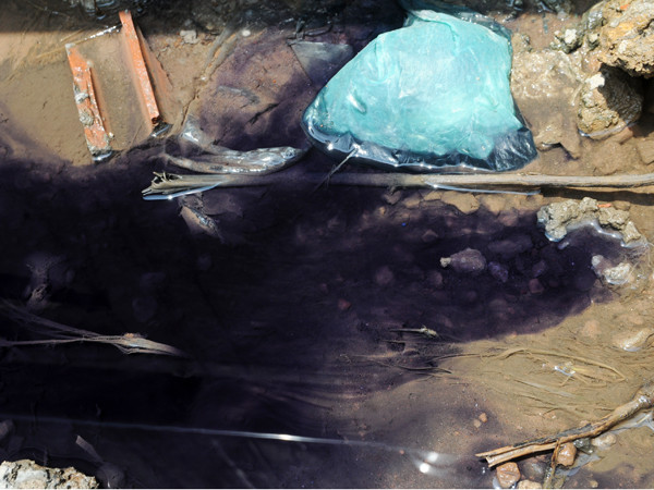 Nước có màu xanh đen rò rỉ tại các rãnh cống phụ phía sau công ty dệt 19-5 gây ô nhiễm. Ảnh: Tuấn Nguyễn