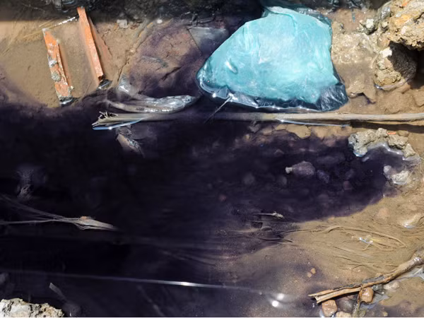 Nước có màu xanh đen rò rỉ tại các rãnh cống phụ phía sau công ty dệt 19-5 gây ô nhiễm. Ảnh: Tuấn Nguyễn