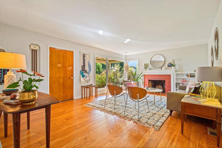 Phòng khách có diện tích lớn, sử dụng nhiều đồ nội thất tối màu với cửa sổ lớn thông ra hiên phía trước nhà.