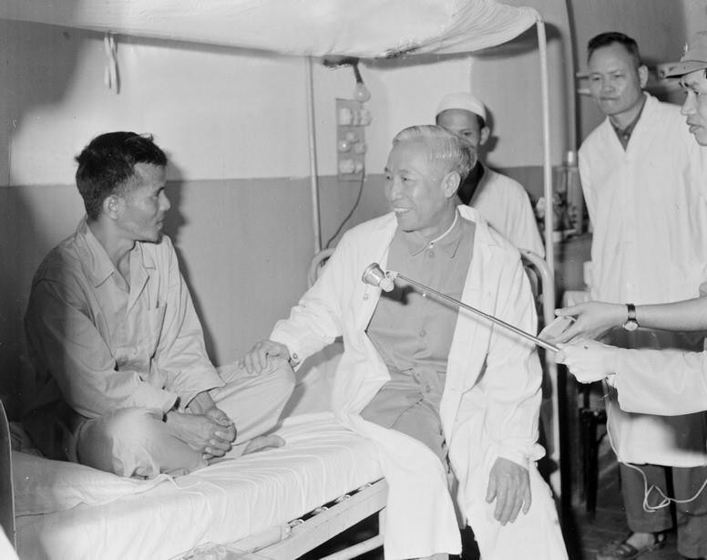 Đồng chí Lê Đức Thọ, Ủy viên Bộ Chính trị, Cố vấn đặc biệt tại Hội nghị Paris về Việt Nam ân cần thăm hỏi Đại úy Từ Minh Kính, sỹ quan liên lạc trong Tổ liên hợp quân sự 4 bên tại khu vực Buôn Ma Thuật, đang nằm điều trị tại Quân y viện 108 (3/1973). (Ảnh: TTXVN)