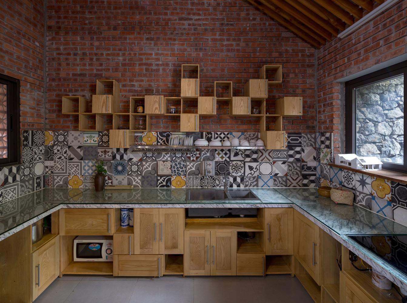 Từ sân lên nhà có một bậc tam cấp bằng đá, hai bên đặt nhiều chậu cây cảnh. Qua bậc tam cấp tiến vào nhà sẽ bắt gặp khu vực phòng khách, bếp nấu ăn.