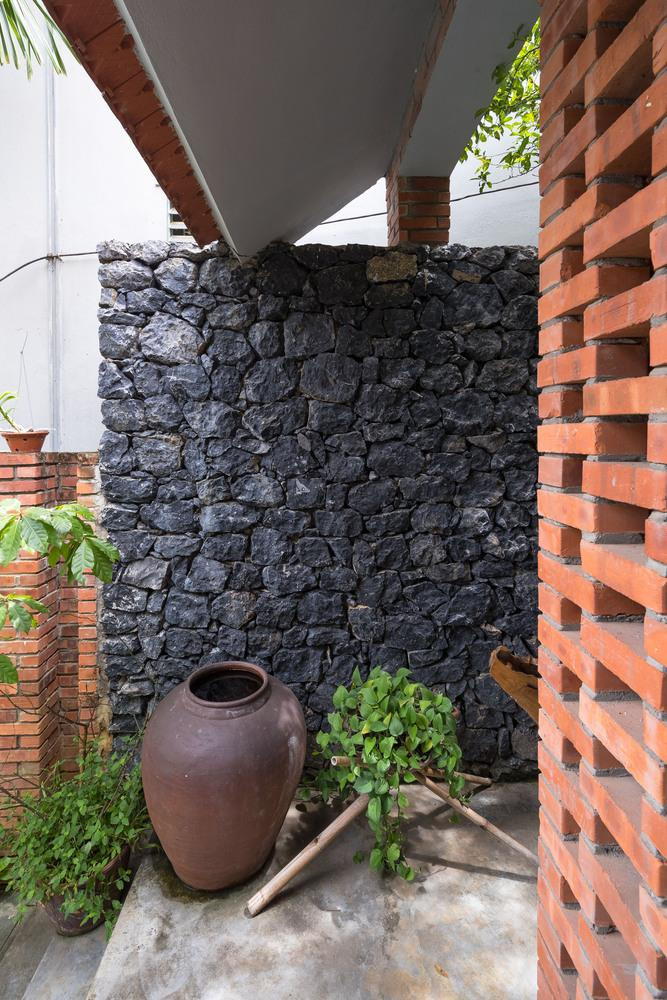 Hai bên nhà được bao quanh bởi những bức tường rào được xây bằng đá đen sẫm, lấy từ quá trình đào những trụ móng và san nền cho các khoảng sân.