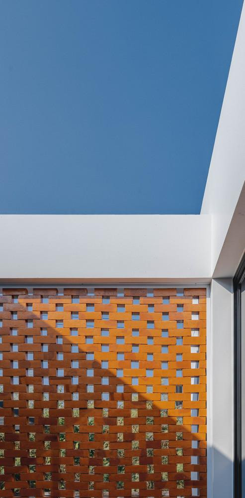 Phần sân giữa này ngăn cách với thế giới bên ngoài bằng bức tường gạch đỏ xây theo dạng lưới, đây cũng chính là điểm nhấn của tổng thể ngôi nhà có sơn ngoại thất màu trắng.