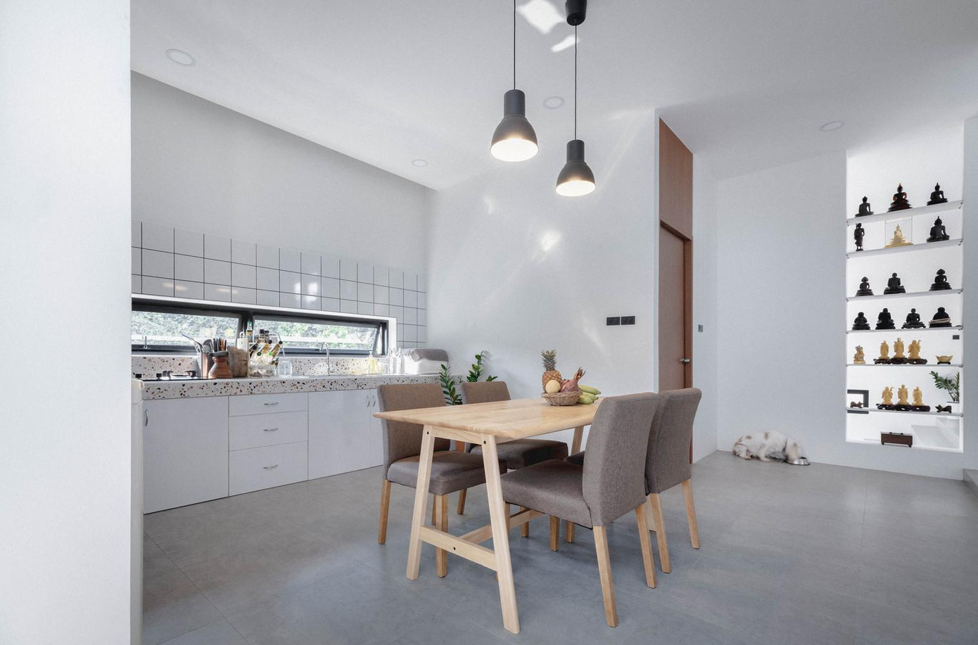 Phòng khách và bếp được ngăn cách bằng một kệ bày tượng phật. Trong bếp cũng có hệ thống ô thoáng để cung cấp ánh sáng và thông gió tự nhiên.