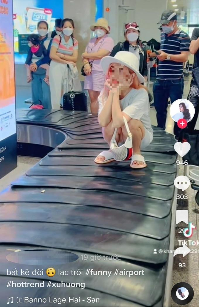 Cô gái ngồi trên băng chuyền hành lý ở sân bay.