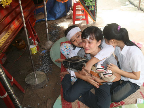 Bà Lê Thị Mấm, mẹ em Nguyễn Văn Hải, suốt 2 ngày qua ngồi cạnh quan tài ôm cặp và giày con khóc thảm thiết. Ảnh: Đăng Lê