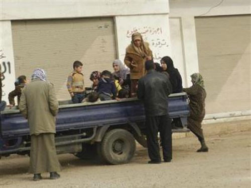 Người dân rời khỏi nhà sau khi đợt oanh tạc của quân chính phủ ở Houla, gần Homs, hôm 3-12