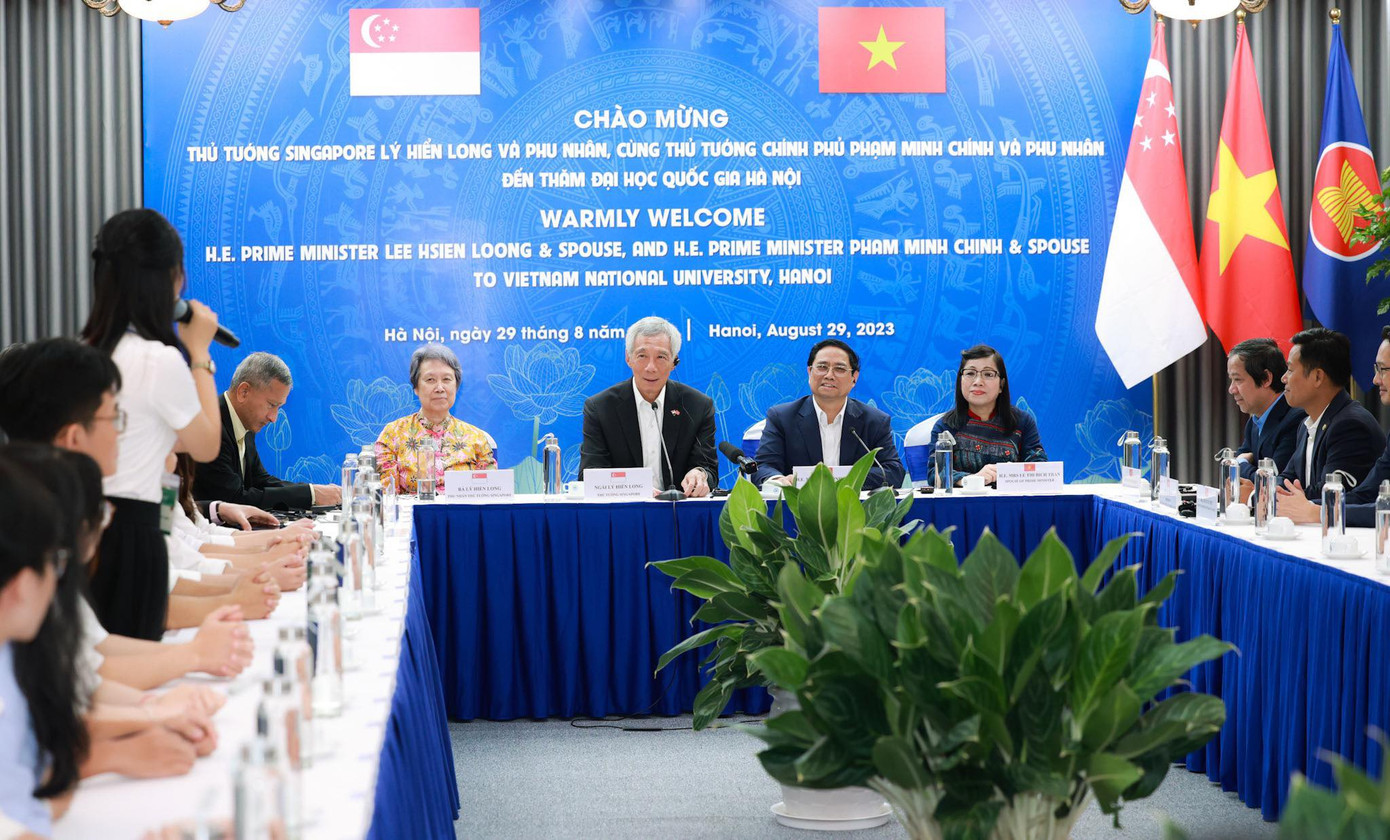 Thủ tướng Phạm Minh Chính (thứ hai từ phải sang) và Thủ tướng Singapore Lý Hiển Long (thứ hai từ trái sang) cùng hai Phu nhân giao lưu cùng sinh viên ĐHQGHN sáng nay. Ảnh: Như Ý