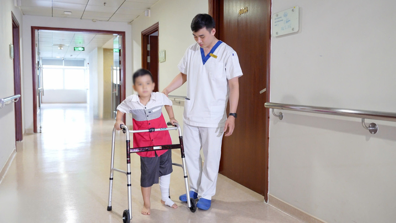 Bé Đ tập đi sau ca phẫu thuật.