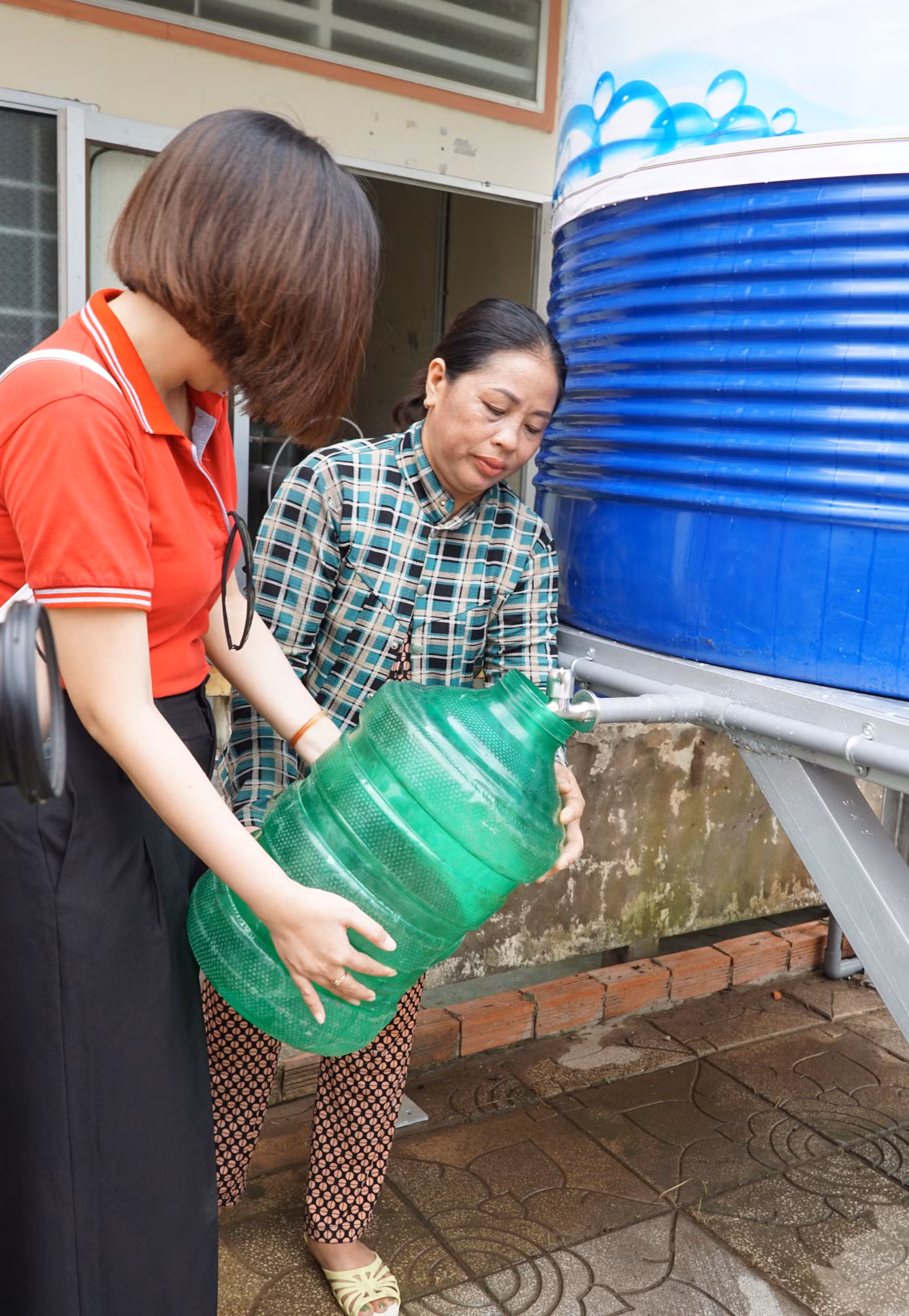 Nhân viên Keppel đang giúp người dân hứng những bình nước sạch đầu tiên
