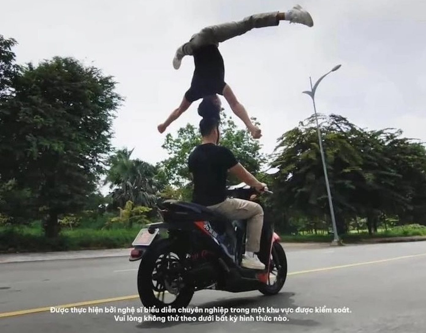 2 anh em Quốc Cơ- Quốc Nghiệp biểu diễn chồng đầu đi xe máy. Ảnh cắt từ Clip.