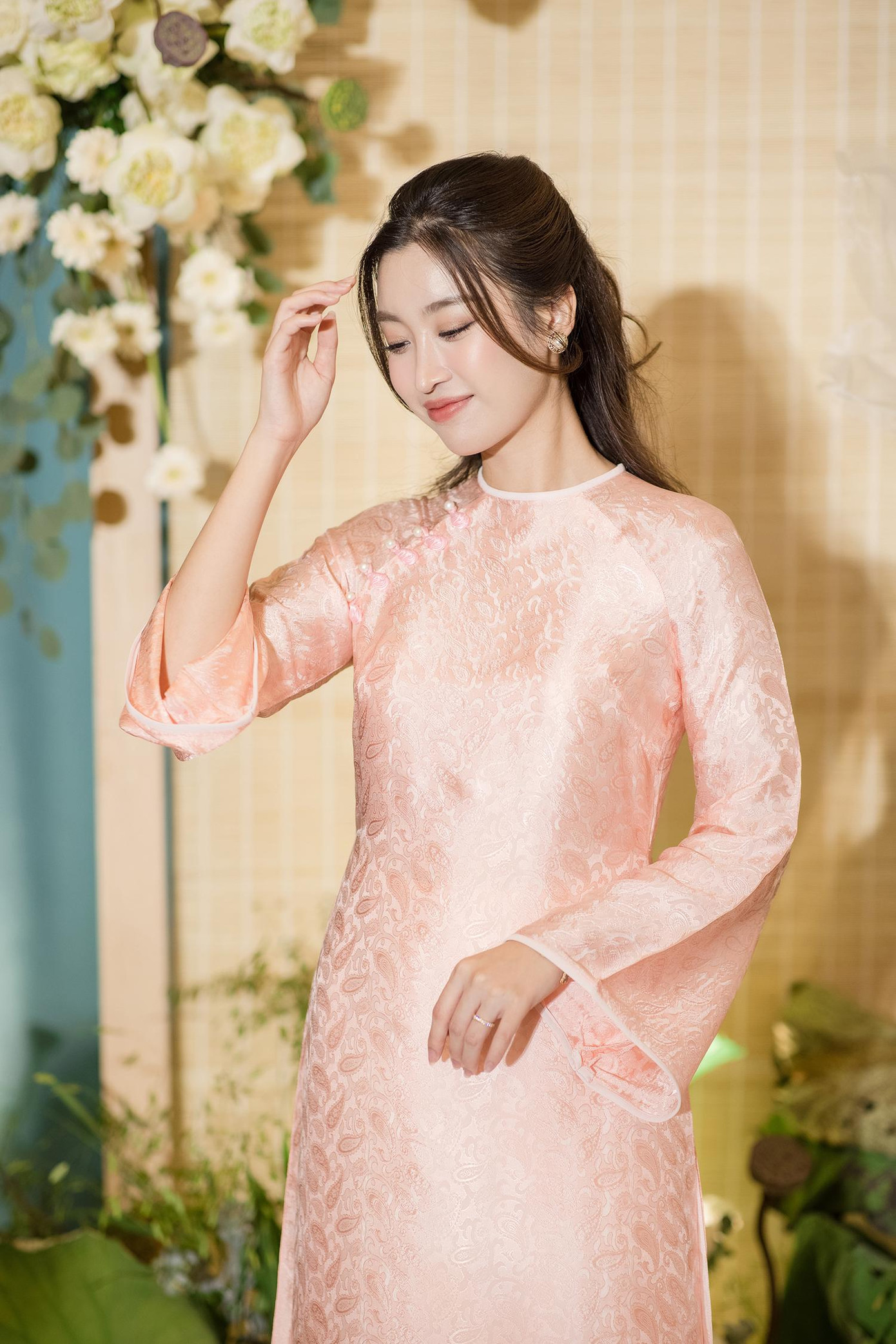 Hoa hậu Đỗ Mỹ Linh diện bộ áo dài tông hồng pastel ngọt ngào. Áo dài của Mỹ Linh được thiết kế kiểu trơn, không có cổ áo. Người đẹp trang điểm nhẹ nhàng để phù hợp không gian tiệc cưới.