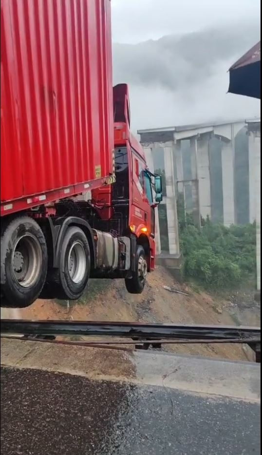 Tài xế mắc kẹt trong cabin xe container nằm cheo leo trên miệng vực sâu 100m. (Ảnh: The Standard)