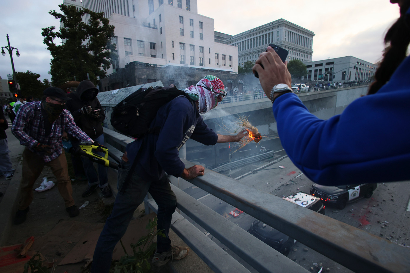 Người biểu tình ném đồ vật vào xe cảnh sát trên đường phố Los Angeles. Ảnh: AP