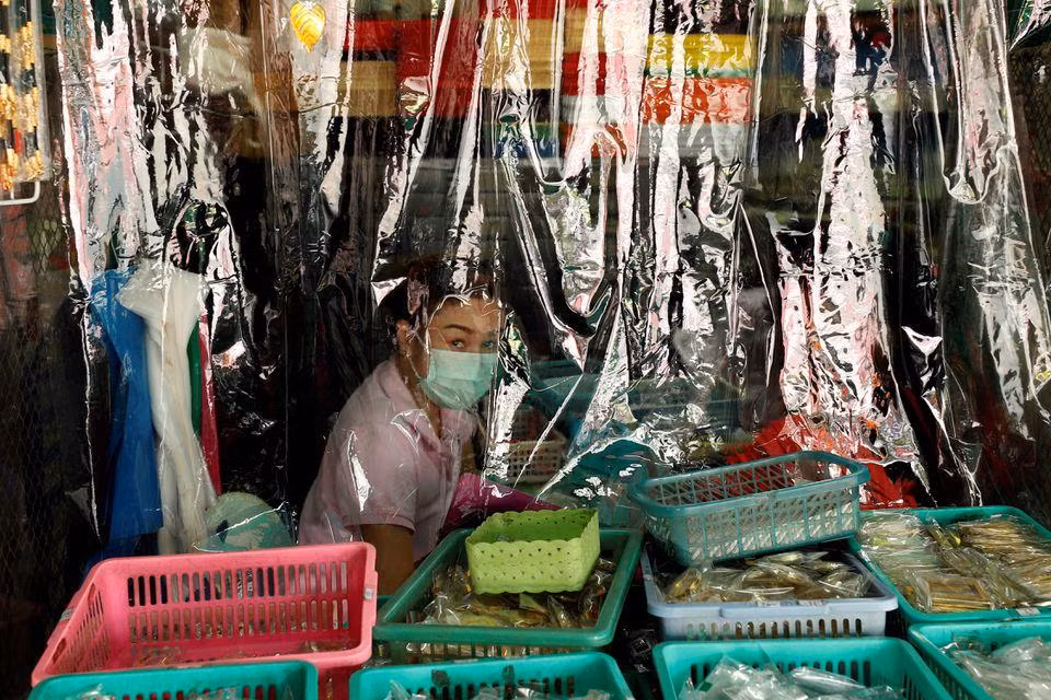 Một người bán hàng treo rèm nilon để hạn chế nguy cơ lây lan virus. Ảnh: Reuters