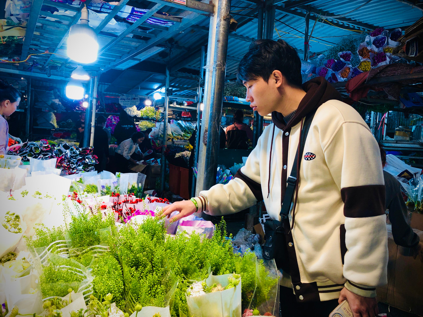 Nhiều bạn trẻ cũng lặn lội đến chợ hoa từ nửa đêm để chọn mua hoa làm quà. Anh Nguyễn Quang Thái (áo trắng, 22 tuổi) cho biết: "8/3 năm nào mình cũng đến đây mua hoa về cắm để tặng bà và mẹ của mình vì ở đây có nhiều mẫu mã và giá cả bao giờ cũng rẻ hơn những chỗ khác". Ảnh: Ngọc Hân