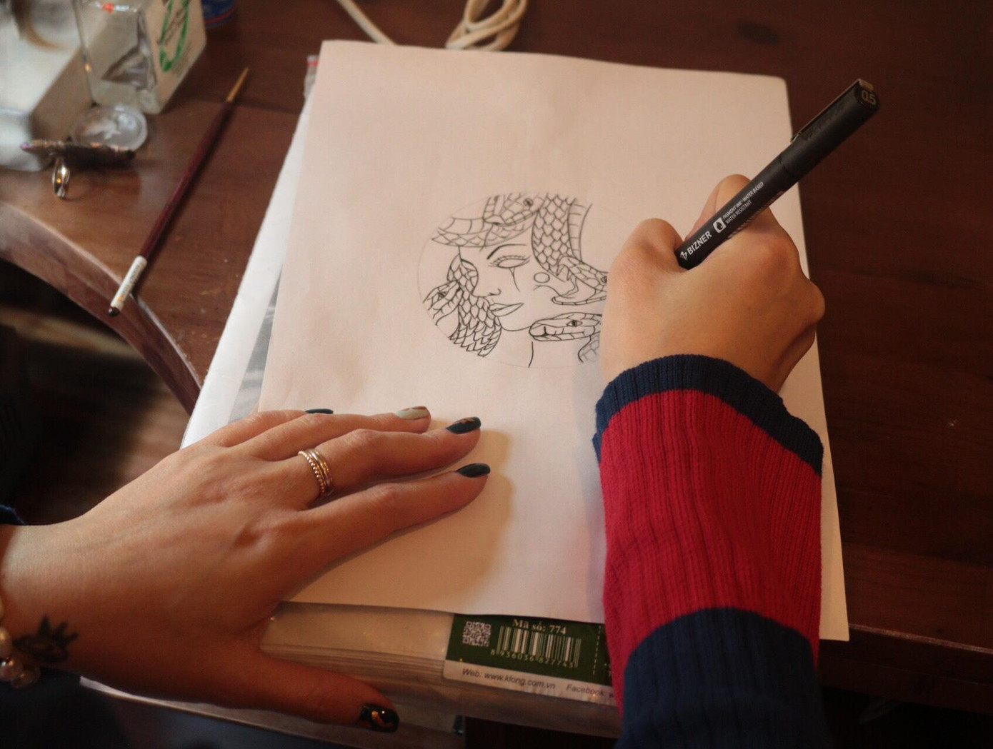 Chị Dương giới thiệu các bước để hoàn thiện một tác phẩm trên mặt đồng hồ, sẽ bao gồm các bước từ phác thảo trên giấy, chuyển hình lên mặt số, vẽ màu, dát vàng, khảm đa vật liệu, phủ bảo vệ, lắp lên máy đến hoàn thiện dây da.