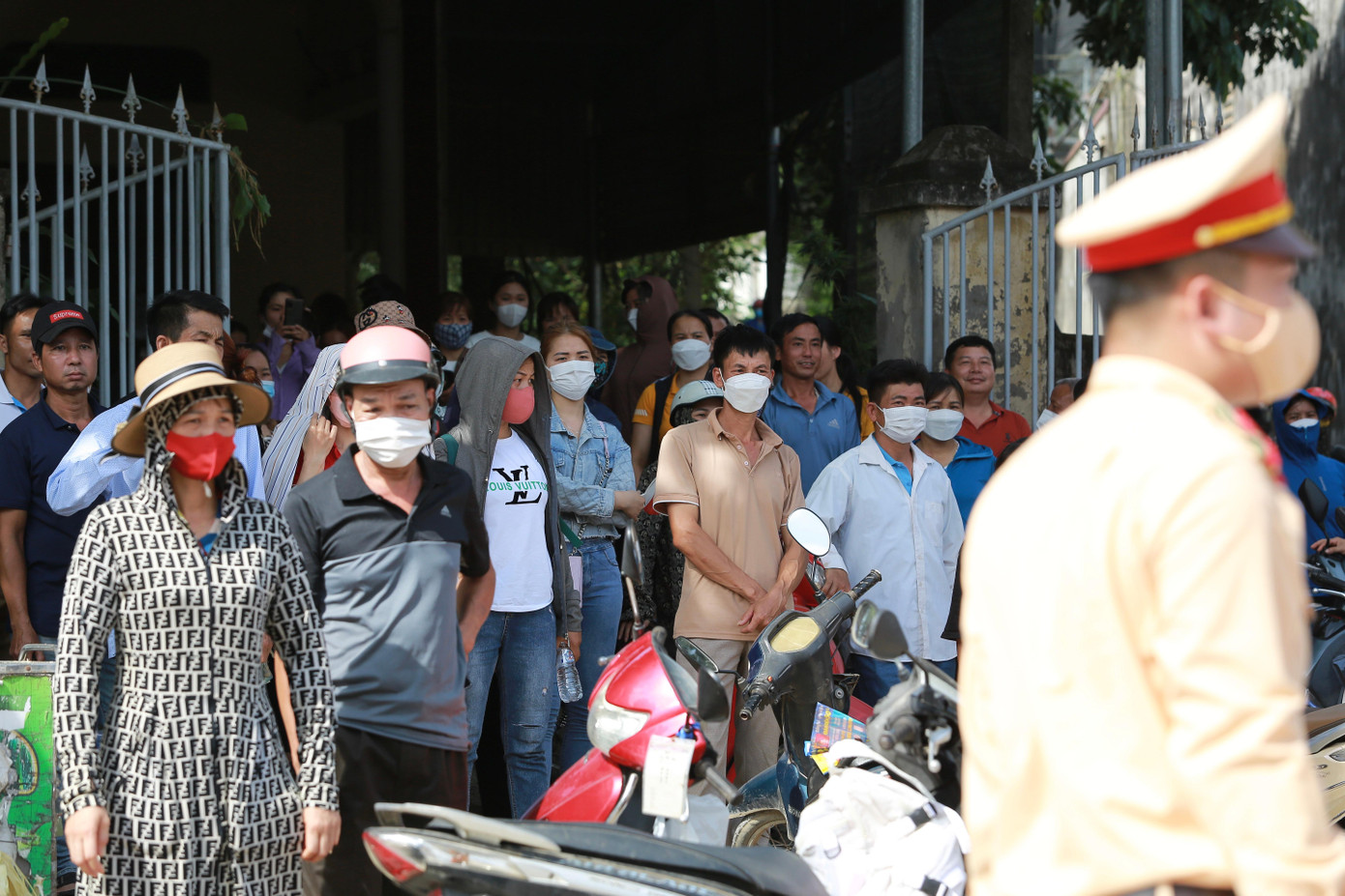 Phụ huynh tá túc ở những bóng râm quanh cổng trường nóng lòng đợi con.