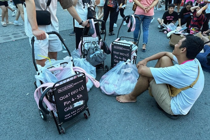 Nhóm sinh viên ngồi bán hàng vạ vật trước cổng sân Mỹ Đình. Quạt đã hạ giá 50% nhưng vẫn không có người mua (Ảnh: Thanh Thúy).