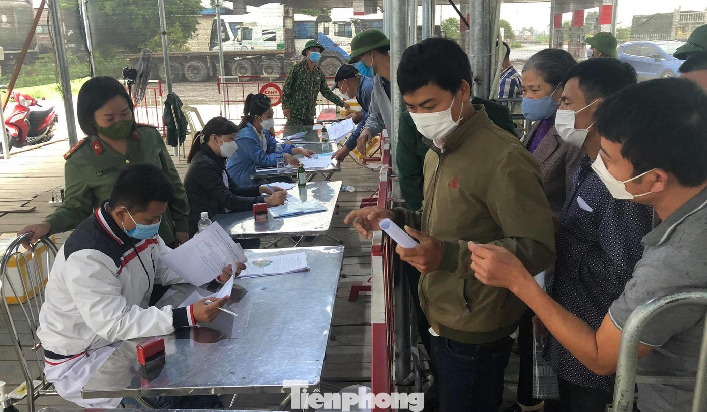 Do lưu lượng phương tiện qua QL10 rất lớn, chốt kiểm soát COVID-19 tại cầu Nghìn luôn trong tình trạng hoạt động hết công suất. Trong ảnh: Người dân xếp hàng nộp tờ khai y tế.