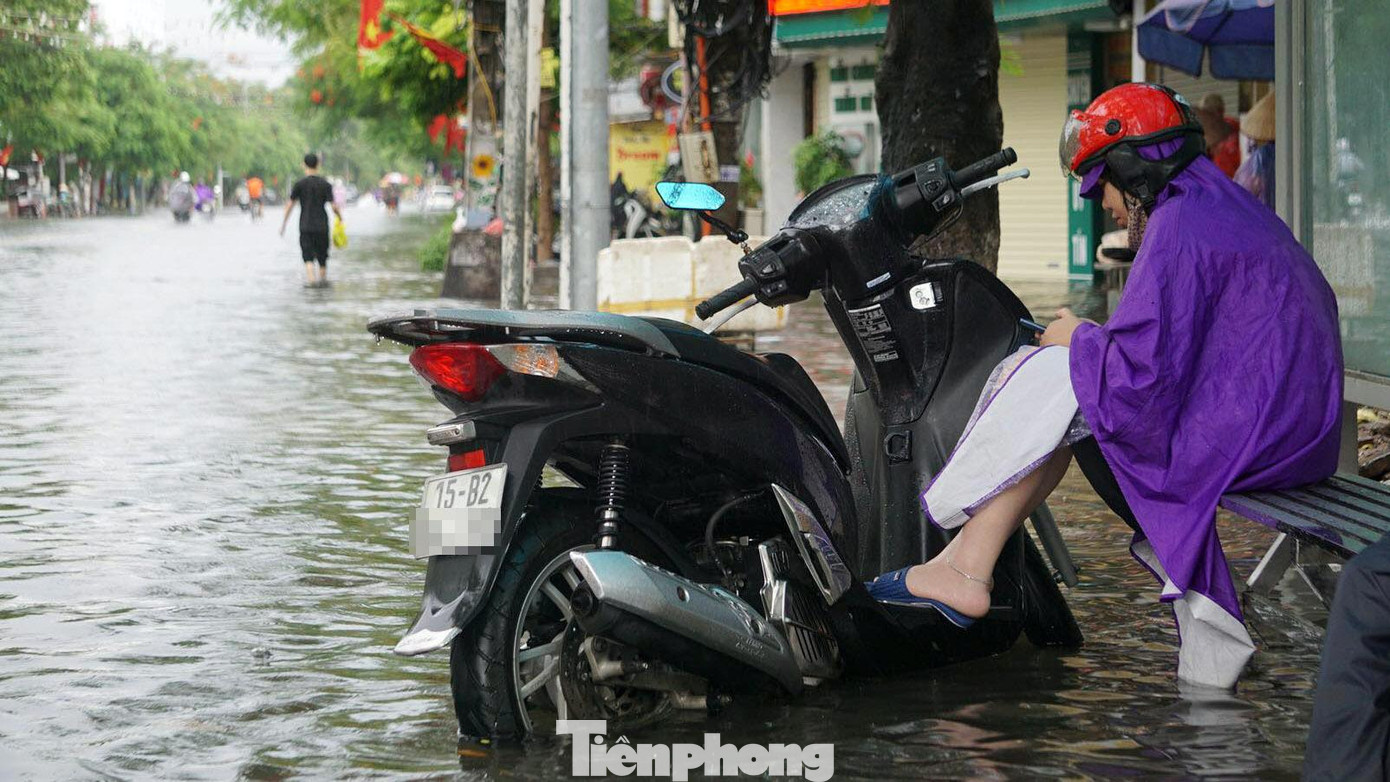 Xe chết máy, một người phụ nữ ngồi chờ tại điểm dừng xe buýt trên phố Lạch Tray chờ người thân hỗ trợ.
