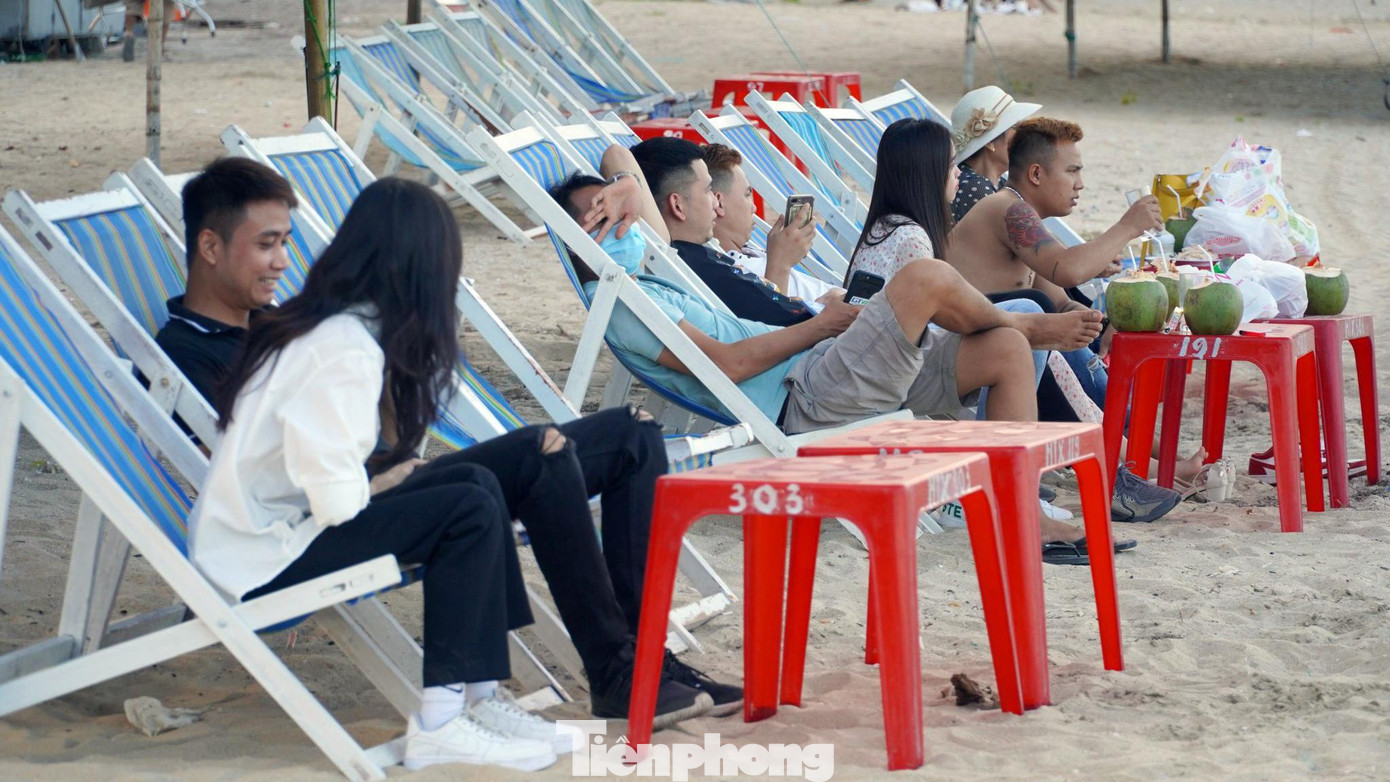 Một số bạn trẻ ngồi trên bờ cát hóng gió, trò chuyện.